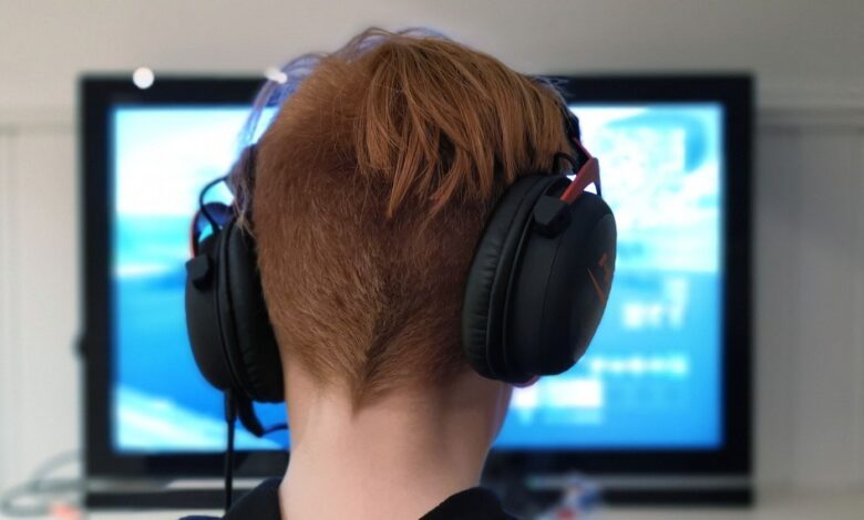 man wearing gaming headphones in front of screen